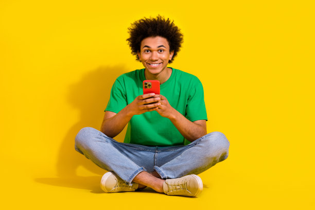 时髦酷的家伙穿着绿色t恤手臂后面的头坐在豆袋空的空间孤立的黄色背景的全身照片图片下载