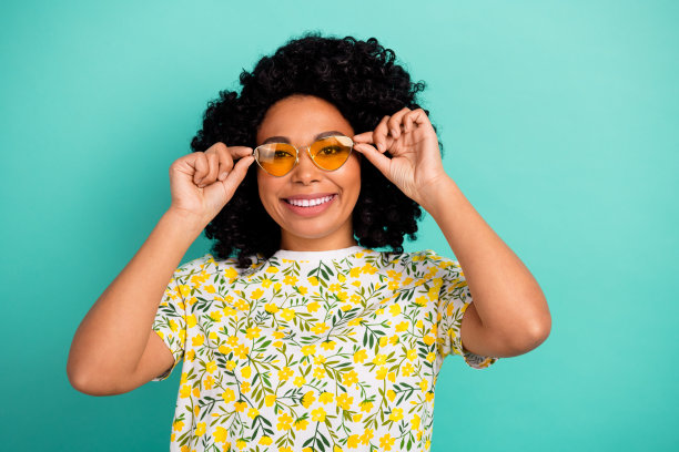 照片上光鲜迷人的女士穿着印花t恤，手臂戴着墨镜，空白空间孤立的蓝绿色背景图片下载