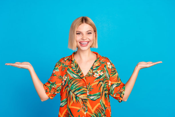 照片正面漂亮可爱的女孩穿着时尚的印花衣服，双手抱空空间孤立在蓝色的背景图片下载