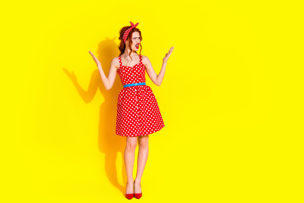 照片中迷人可爱的愤怒的疯女人穿着红色的裙子，在生动的黄色背景上看起来空无一物图片下载