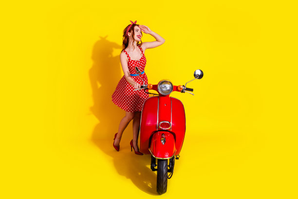 照片中可爱开朗的可爱女士穿着红色时髦的沙拉芬轻便摩托车，在黄色的背景下显得遥远孤立图片下载