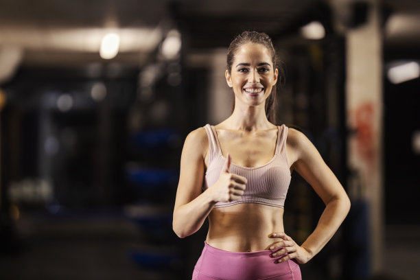健美的女运动员在健身房里竖起大拇指的照片。图片下载