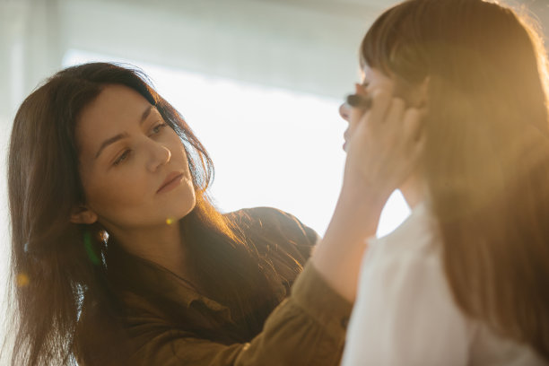 一位化妆师在摄影棚里为一个小女孩准备照片。图片下载