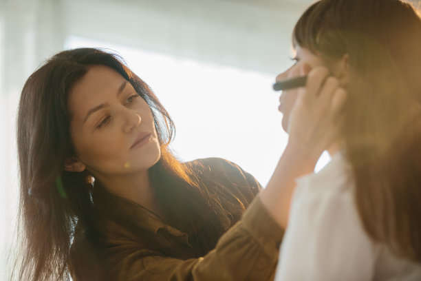 美丽的女化妆师在拍摄前为模特在工作室化妆。图片下载