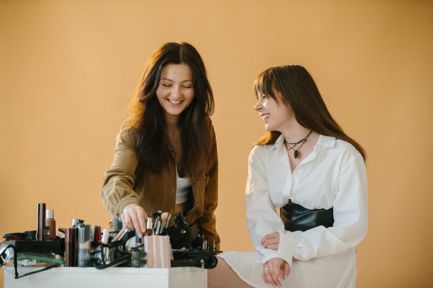 化妆师在摄影工作室用米色背景为女模特做准备图片下载