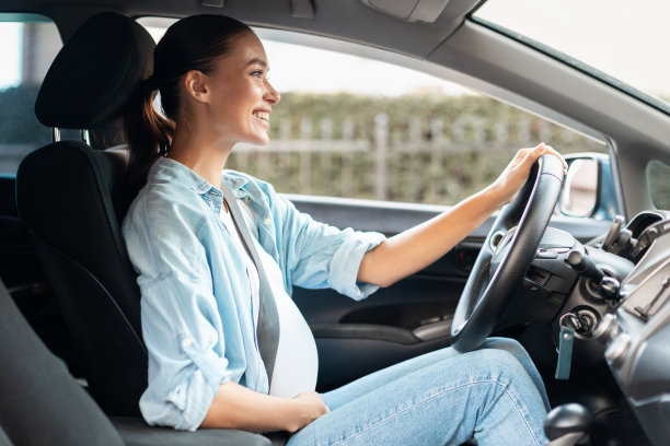 年轻的准妈妈坐在汽车的驾驶座上开车图片下载