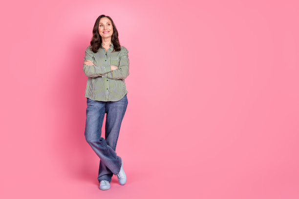开朗漂亮的女士穿着条纹衬衫的全长照片手臂折叠看着空空间孤立的粉红色背景图片下载