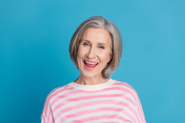 漂亮的高级妇女的照片肖像，微笑，大笑，穿着时髦的条纹服装，孤立的蓝色背景图片下载