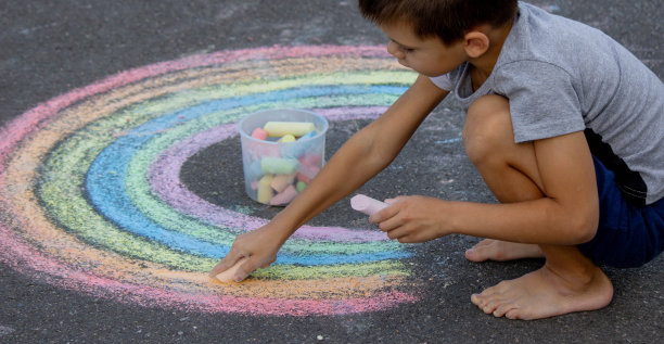 男孩用粉笔在柏油路上画画。有选择性的重点图片下载