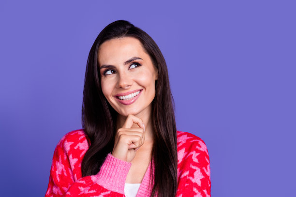 照片中开朗漂亮的女人穿着时髦的印花衣服，手臂触摸脸，在紫色的背景上看起来空无一物图片下载