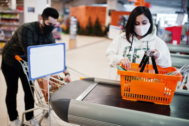 疫情期间，亚洲夫妇戴着防护口罩在超市购物，在收银台结账图片下载