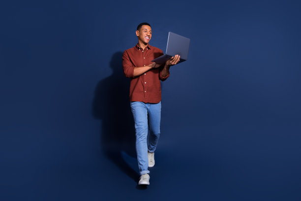 时髦酷的家伙穿着棕色衬衫聊天现代设备空旷的空间孤立的蓝色背景的全长照片图片下载