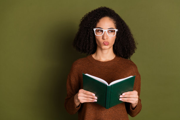 漂亮的年轻女子的肖像书看空空间穿毛衣孤立的卡其色背景图片下载
