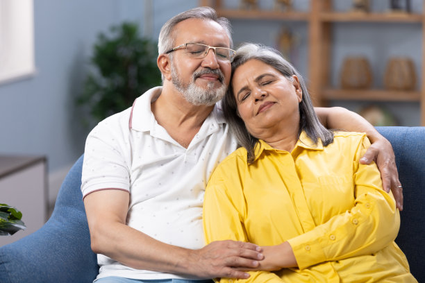 老夫妇闭上眼睛，放松在客厅沙发上舒适的午睡，轻松的生活方式和退休在家里，爱，照顾和睡在沙发上的老夫妇一起在公寓库存照片图片下载