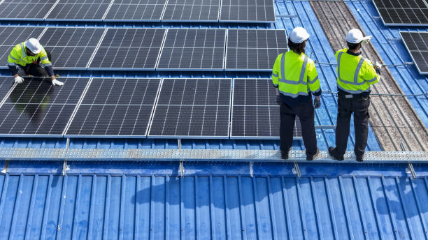 工人技术人员正在屋顶上建造太阳能电池板系统。安装太阳能光伏板系统。男技师走在屋顶结构上检查光伏太阳能组件。图片下载