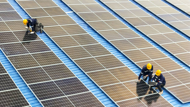 光伏工程师在屋顶仓库工作。检查和修理太阳能板设备的屋顶结构。工程师工作设置电力可再生能源的可持续性。图片下载