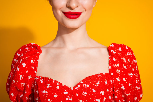 剪短的照片可爱的年轻女士欢快的微笑，润发，化妆，穿着时尚的红色服装孤立的黄色背景图片下载