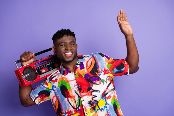 漂亮的年轻人的照片携带立体声音箱穿着衬衫孤立的紫色背景图片下载