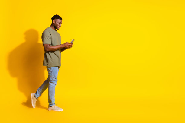 照片正面迷人的好男人穿着卡其布时尚的衣服拿着小工具走空空间孤立在黄色的背景图片下载