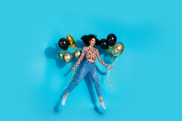 照片中开朗、积极、有趣的女人穿着时髦的衣服，拿着气球，看起来空无一物，孤立在蓝色背景上图片下载