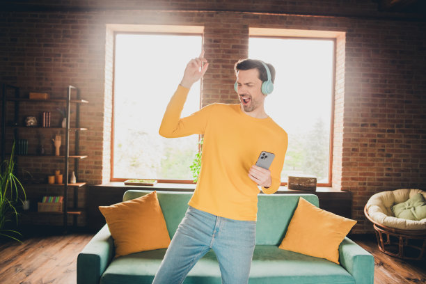 照片肖像英俊成熟的男人耳机听音乐跳舞设备穿着黄色的衣服舒适的日光家室内客厅图片下载