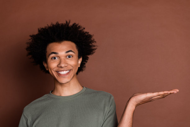 照片中年轻英俊的模特穿着灰色t恤，手牵着手展示产品的空白空间，广告被隔离在棕色背景上图片下载