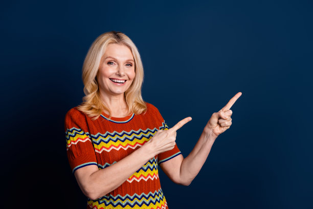 照片中开朗可爱的女人穿着时尚的条纹衣服，推荐在深蓝色背景上隔离空的空间图片下载