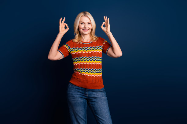 照片中开朗的好女人穿着时髦的衣服，双手ok的标志孤立在深蓝色的背景上图片下载