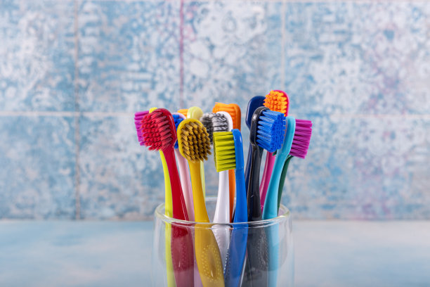 背景模糊的陶瓷碗牙刷。早上卫生。浴室配件图片。蓝色背景的牙刷。彩色牙刷，健康牙齿理念。图片下载