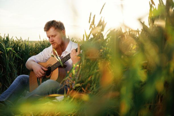 专心致志地弹吉他。穿白衬衫的男人在农田里图片下载
