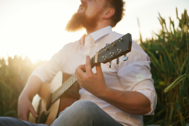 专心致志地弹吉他。穿白衬衫的男人在农田里图片下载