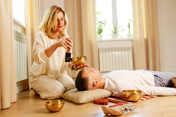 女子在玩藏式唱碗，为男子按摩冥想图片下载