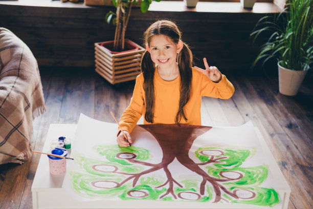 小女孩的照片坐在桌子上画家谱显示v字穿着橙色的衣服舒适的日光家室内客厅图片下载