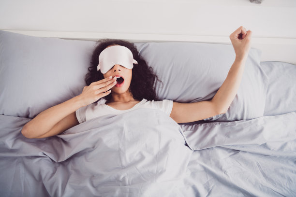 照片年轻迷人的女人躺在床上睡觉打哈欠戴口罩时尚的睡衣柔软舒适的卧室白色的房间里面图片下载