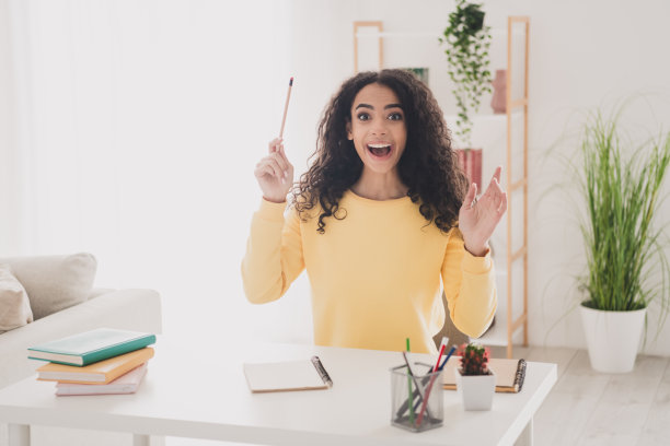 青少年的照片肖像年轻的卷发美国惊讶女孩在黄色衬衫坐在工作场所做家庭作业的大学室内图片下载
