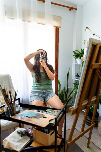 一位艺术家在她的艺术工作室里拿着一台旧相机的肖像。图片下载