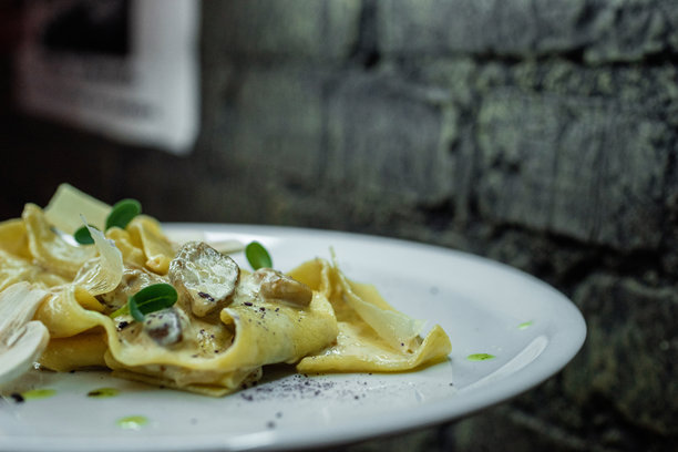 美味的煮面条配上奶油酱、香槟酒、绿色蔬菜和鸡柳，背景是酒吧里的灰色砖墙。吃晚饭的时间了。特写镜头。图片下载