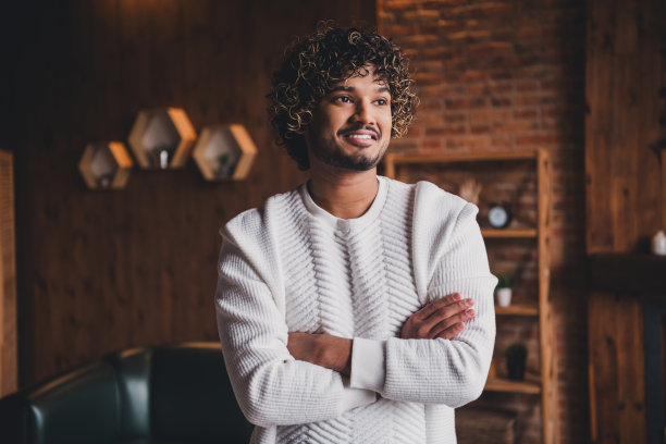 英俊的好心情的家伙穿着白色的运动衫双臂交叉在室内休息房间家房子的照片图片下载