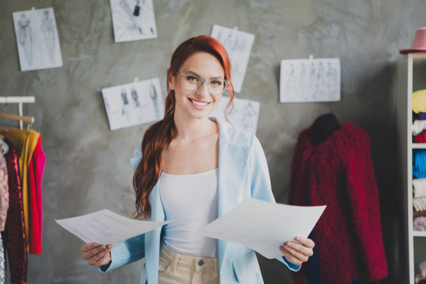 职业女设计师在工作场所拿着两张衣服收集纸的照片图片下载