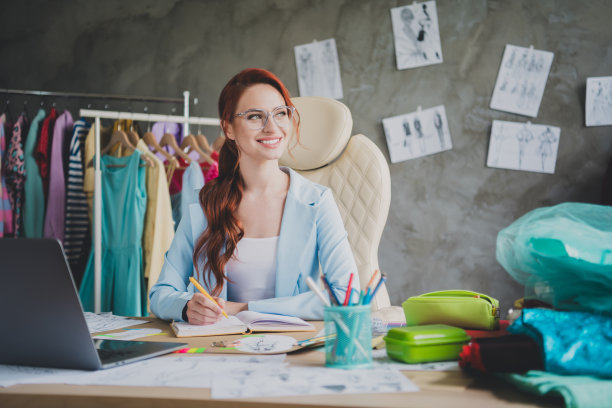 微笑的女士的照片坐在桌子上写在册子上，看侧面在商店办公室图片下载