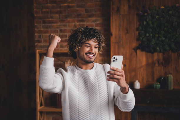 时髦的酷家伙穿着白色套头衫赢得游戏的照片在室内的房子公寓房间图片下载