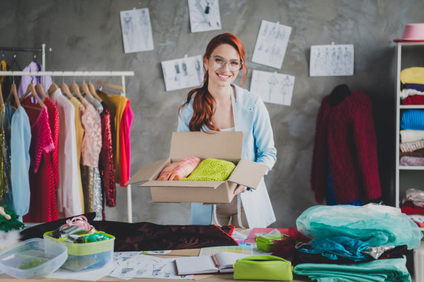 照片漂亮优雅的服装设计师女人拿着衣服订购盒阁楼室内办公室室内图片下载