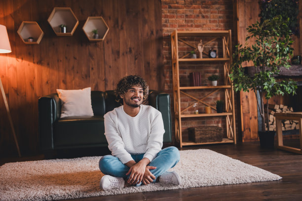 照片中穿着白色套头衫的开朗积极的小伙子微笑着呆在家里的房子里图片下载