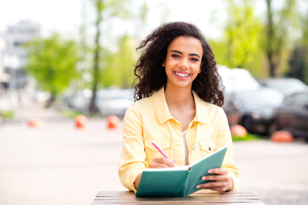 漂亮的年轻女孩的照片，写笔记本，新鲜的空气，街上的咖啡馆，户外的桌子图片下载