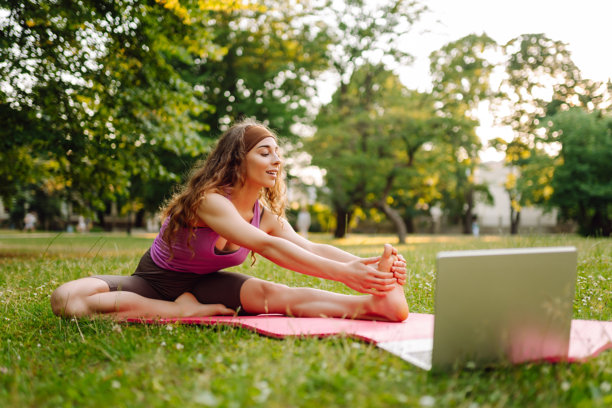 快乐的女人在户外在线练习普拉提课。图片下载