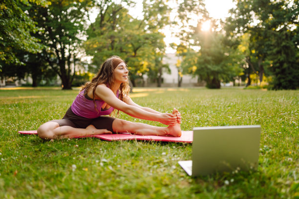 快乐的女人在户外在线练习普拉提课。图片下载