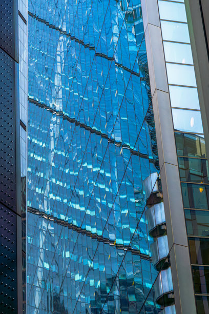 令人惊叹的蓝色玻璃摩天大楼在伦敦金融城的云层中反射光线。图片下载