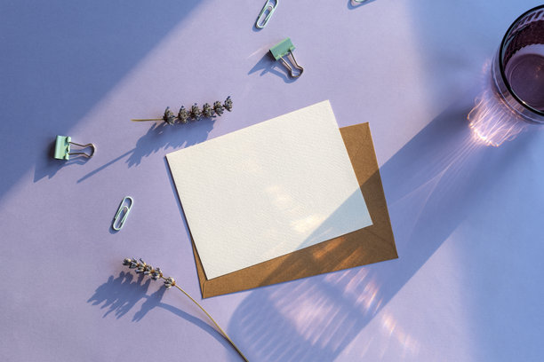 现代夏季文具静物。一杯长长的影子的水，紫色背景上的薰衣草花。空白名片模型。俯视图，平铺图片下载