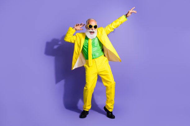 照片中，开朗、快乐、有趣的老人穿着时尚、鲜艳的黄色服装，孤立在紫色背景上的舞蹈俱乐部图片下载