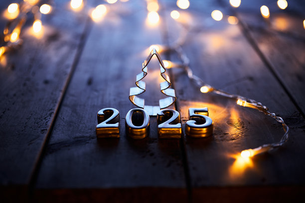 2025年新年庆祝活动，木制桌子上有金属数字和圣诞树轮廓图片下载